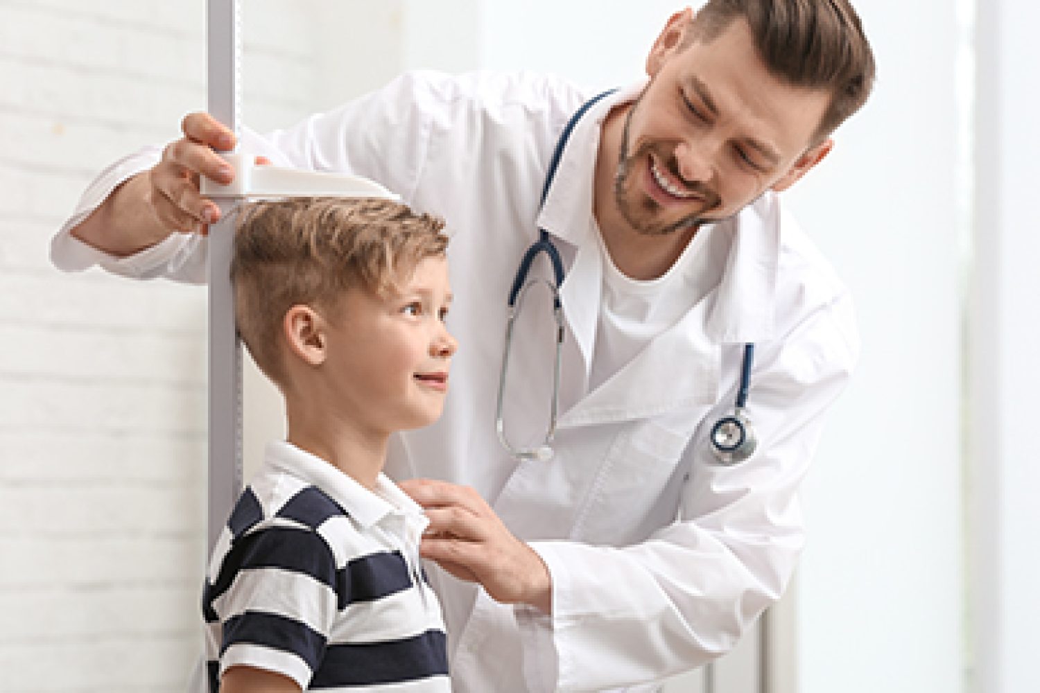 Doctor measuring little boy's height in hospital